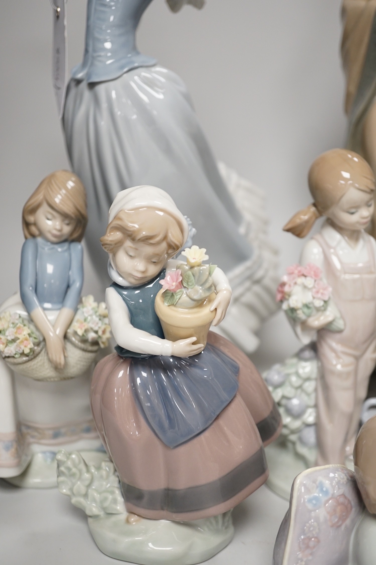 Seven Lladro and two Nao porcelain figures together with another, stuck to base so mark can’t be seen. Tallest 38cm